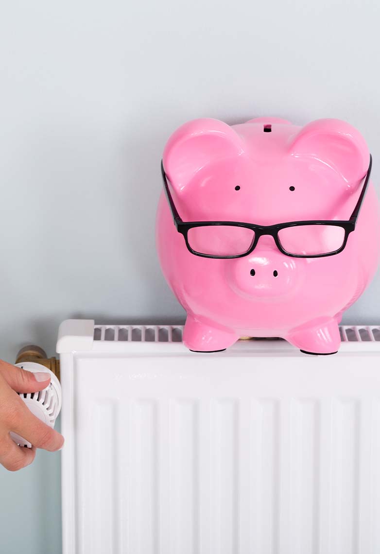 Person adjusting radiator with piggy bank on top Person adjusting radiator with piggy bank on top
